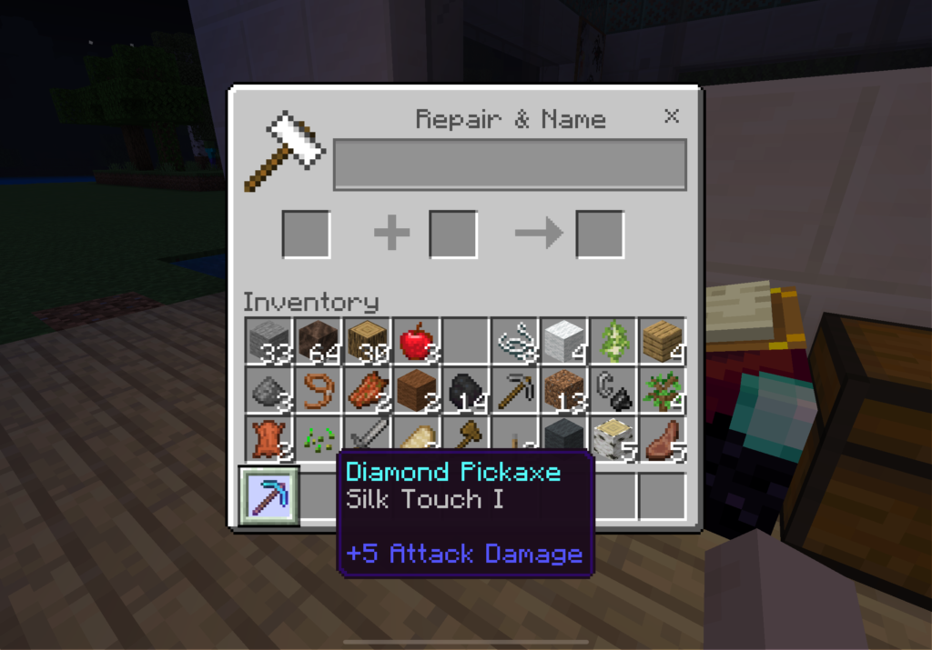 This Minecraft screenshot shows the player's inventory and anvil interface. The player has just enchanted a diamond pickaxe with the "Silk Touch I" enchantment, which is visible in the inventory with a tooltip indicating the enchantment and a +5 attack damage. The inventory is filled with various items, including cobblestone, oak planks, an apple, a lead, leather, and more. In the background, there is an enchanting table and a chest. The interface is open to the "Repair & Name" screen, but no items are currently in the anvil slots.