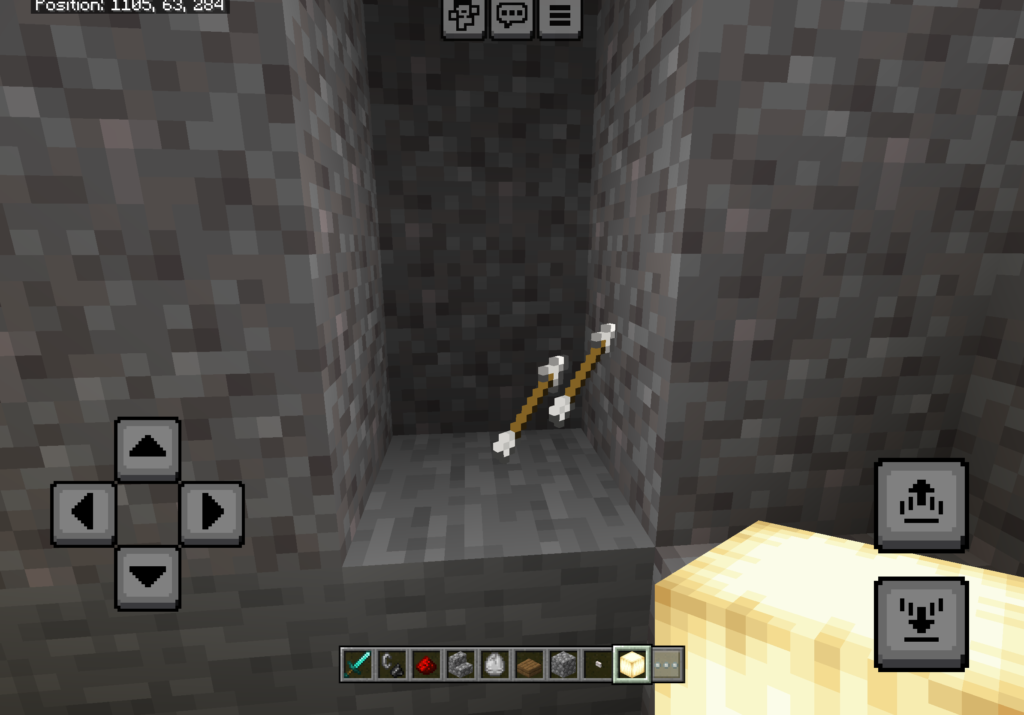 Minecraft gameplay screen showing a narrow stone tunnel with two arrows stuck in the wall at the end. On screen mobile controls and inventory bar are visible, indicating the player is exploring or mining underground.